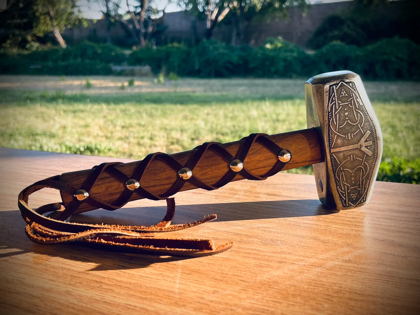 A forged hammer with an engraved head and a leather-wrapped handle