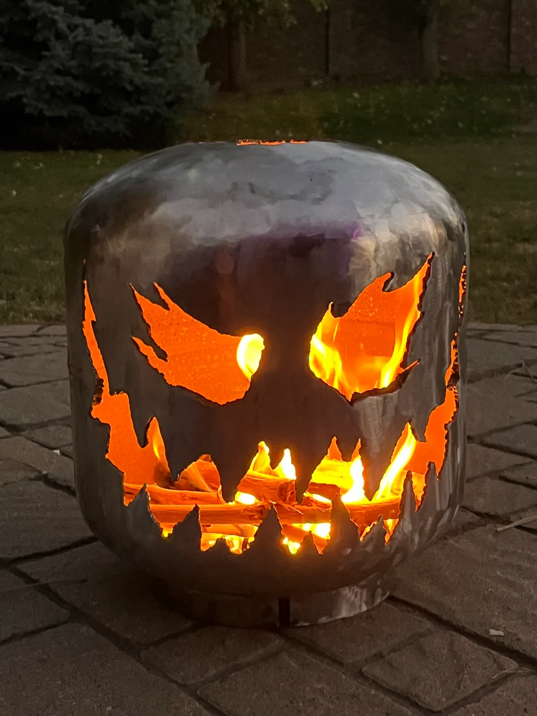 A propane tank cut into a jack-o'-lantern, lit from the fire inside